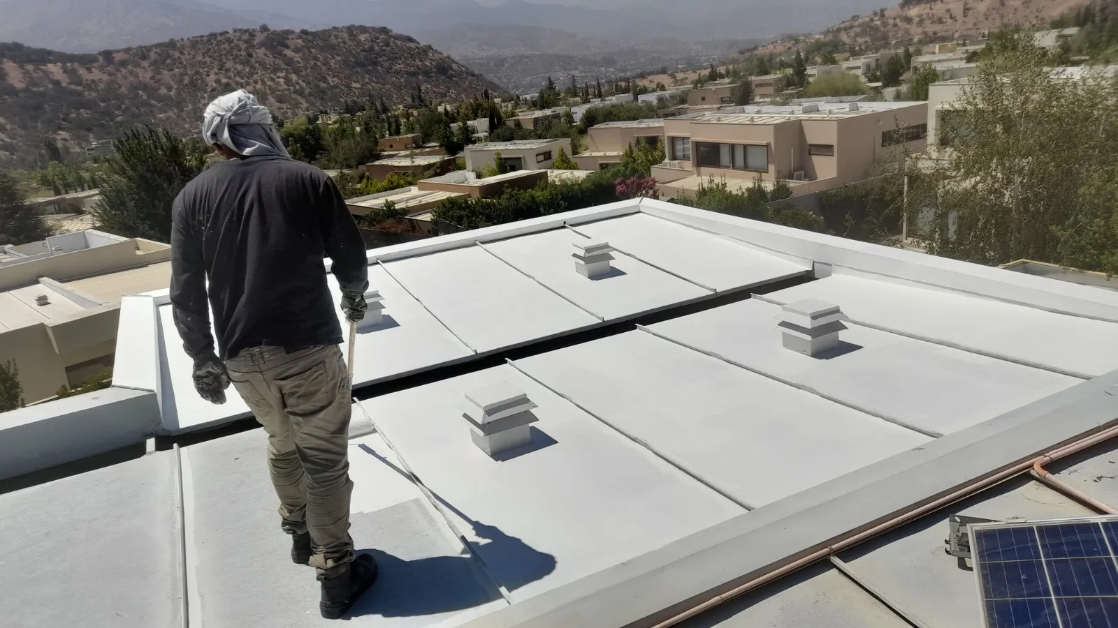 Técnico trabajando sobre una cubierta impermeabilizada de una vivienda en la Región Metropolitana