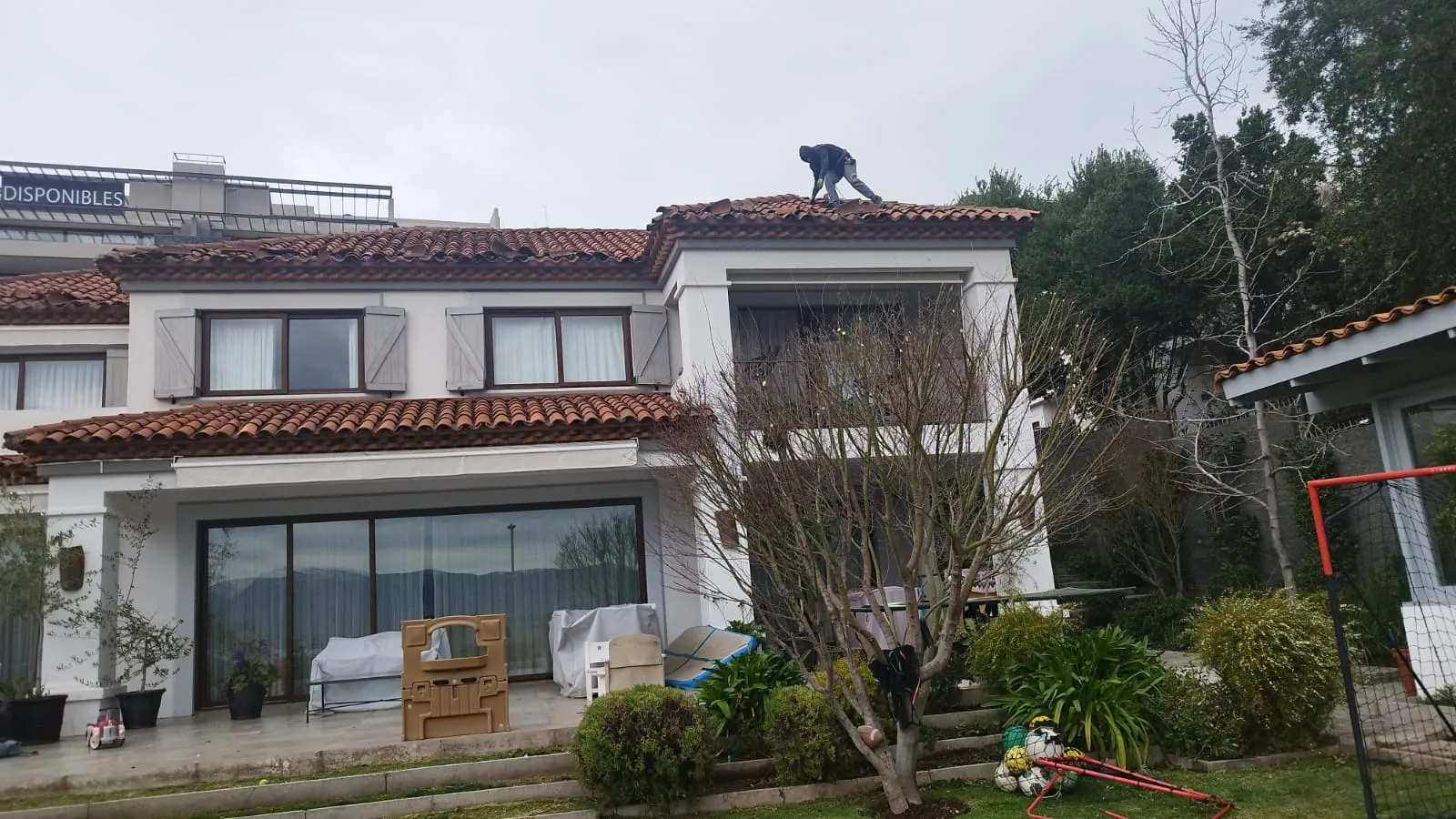 Técnico realizando mantención en el techo de tejas de una casa en Santiago