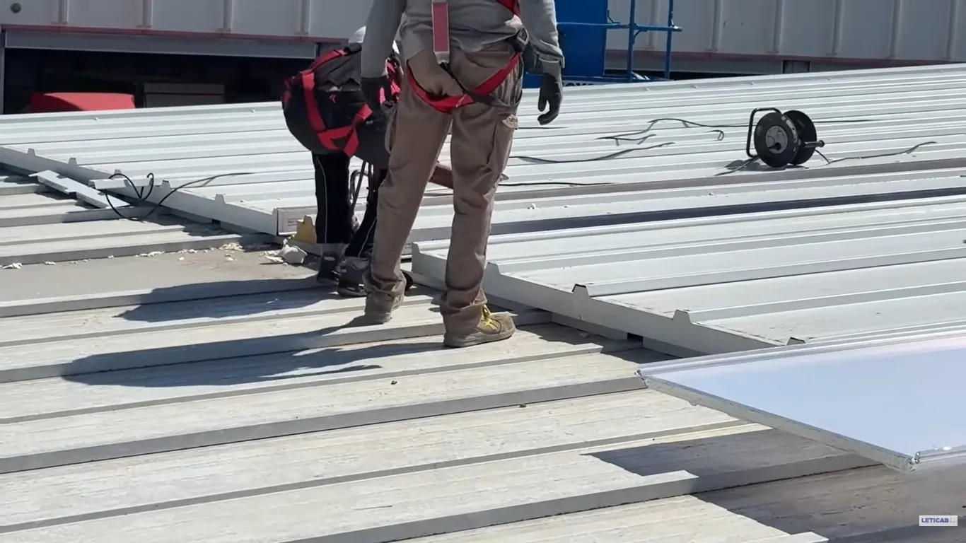 Técnicos con arnés trabajando sobre una cubierta metálica industrial en la Región Metropolitana
