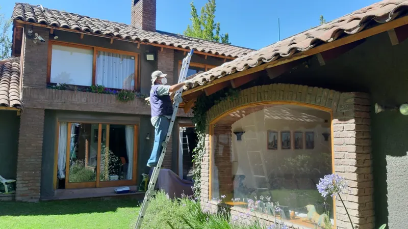 Técnico trabajando en el techo de tejas de una casa en Lo Barnechea