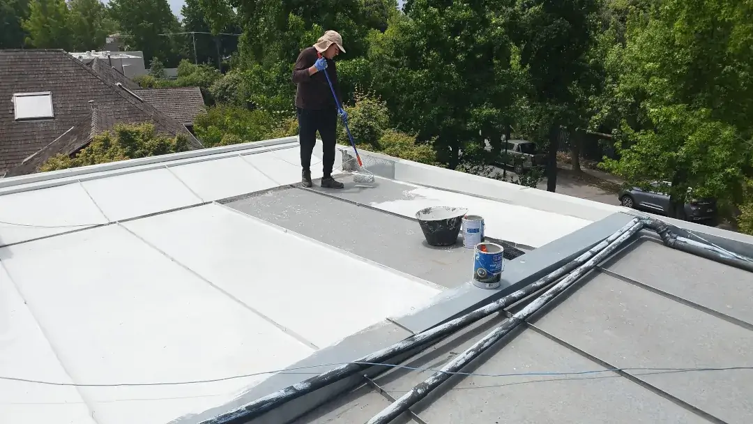 Aplicación manual de recubrimiento impermeable sobre techo de zinc emballetado en vivienda residencial de alto estándar