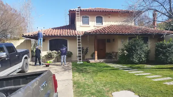 Reparación de tejas en casa de Lo Barnechea tras tormenta, trabajadores restaurando techo de tejas desplazadas por viento fuerte en sector oriente de Santiago, Chile.