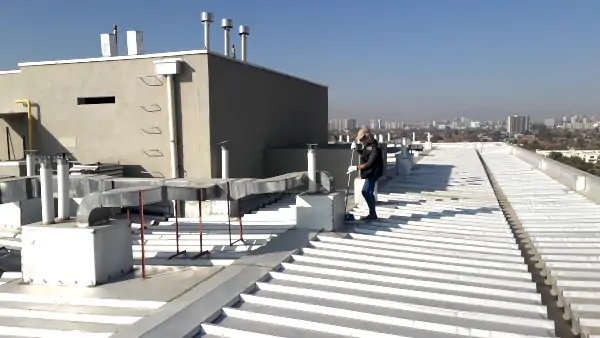 Mantención de techo industrial en edificio corporativo en Santiago de Chile, técnico revisando cubierta metálica y sistemas en azotea.